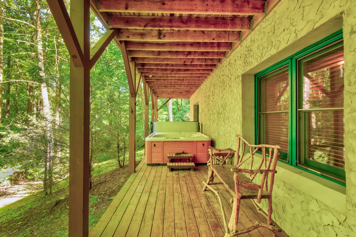 A peaceful exterior view features a hot tub surrounded by wooden chairs and a textured wall, inviting guests to unwind while enjoying the outdoors. The scene is perfect for evening stargazing or morning relaxation.