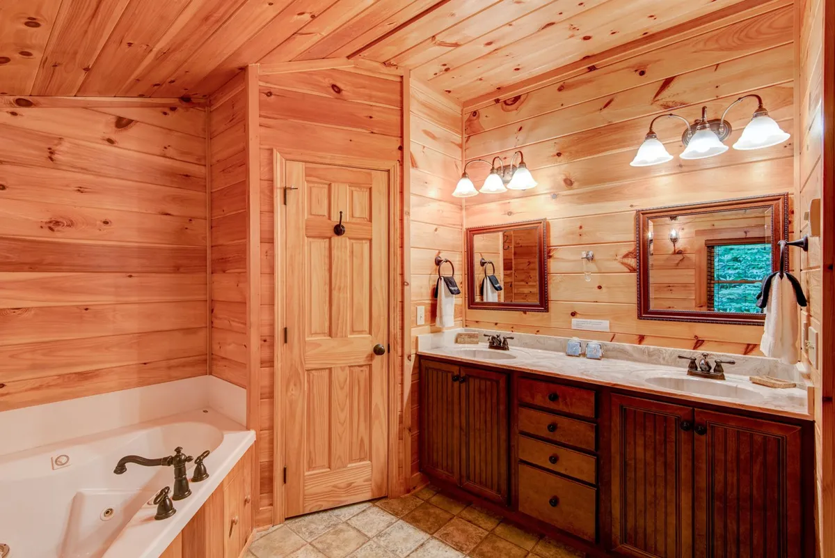 A tranquil bathroom scene with a standalone bathtub, double sink vanity, and wooden accents. The space feels luxurious yet rustic, suggesting opportunities for intimate relaxation and self-care after a day of adventure.