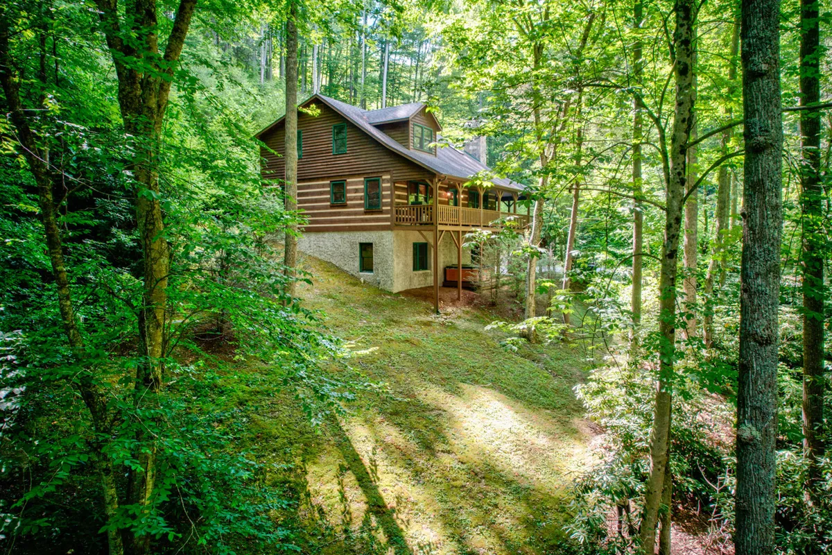 A peaceful exterior shot of the house nestled among trees, featuring a spacious deck area perfect for family gatherings, with nearby forest trails inviting exploration.